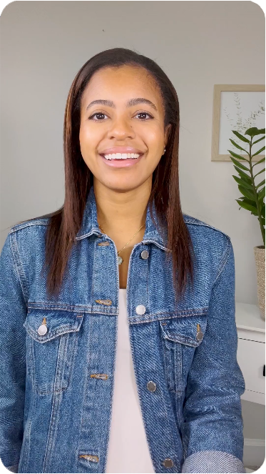 A smiling woman wearing a denim jacket doing a video recording and live stream